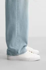 Zapatillas blancas de cuero sintético con cordones, forro interior y plantilla color beige.
