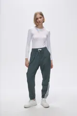Pantalón de jogging color celeste con cintura elástica ajustable con cordón y puños elásticos. Presenta tres tiras verticales blancas en la parte inferior de la pierna.