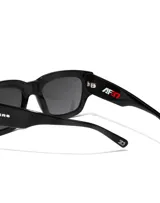 Gafas de sol unisex Hawkers X Augusto Fernandez, de acetato negro con lentes polarizadas negras y logo de la marca en la patilla.