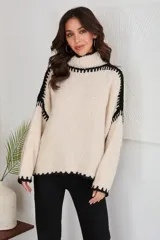 Sweater de mohair color crema con cuello alto y detalles de costura en negro.