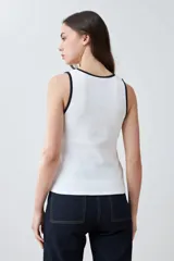 Musculosa de punto canalé color beige con cuello en V y ribete blanco en contraste.