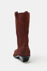 Botín de mujer estilo cowboy color marrón de cuero serraje con puntera fina, tiradores laterales y tacón de 5 cm.