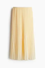 Pollera larga color amarillo pálido, de gasa plisada, con cintura alta con elástico fino y forro interior.