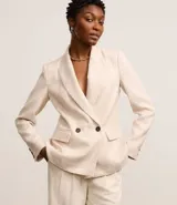 Blazer oversized color beige confeccionado en tweed. Posee cuello inglés, mangas largas, detalles de botones aplicados y solapas que imitan bolsillos.