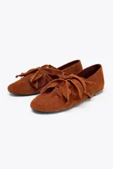 Zapato plano tipo bailarina color marrón de cuero gamuzado, con detalle de flor fantasía en la parte delantera y punta redonda.