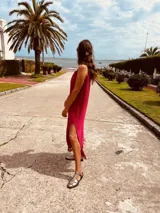 Vestido de fiesta fucsia con escote y espalda de cuero, tajos laterales con hilo metálico y terminación con flecos.