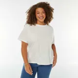 Remera blanca de corte recto, manga corta y cuello redondo. Presenta un bordado calado con motivos florales en el ruedo.