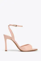 Sandalia color rosa con tacón fino, efecto craquelado, tira ancha en la parte delantera y cierre mediante hebilla metálica a la pulsera del tobillo.
