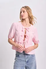 Blusa rosa con rayas verticales blancas, escote redondo con lazos decorativos, mangas cortas abullonadas y corte peplum.