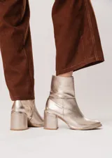 Bota de caña media color champagne de cuero, con horma redonda, taco cuadrado y pequeña plataforma. Cuenta con cierre del lado interno.