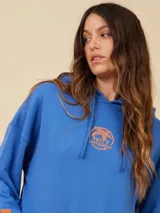 Canguro oversize color crudo con capucha y estampado pequeño en el pecho.
