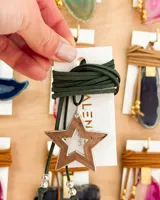Gargantilla con dije de estrella calada color cobre y cordón de gamuza verde oscuro con cuentas plateadas.