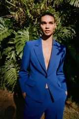 Blazer azul eléctrico de corte entallado, con cuello de solapa, manga larga con hombreras, bolsillos frontales con solapa y cierre frontal con un botón.