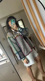 Chaqueta corta de paño de lana azul con detalles de crochet en rojo y verde.