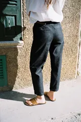 Pantalón de tiro medio con bolsillos frontales y traseros de vivo. Bajo con vuelta. Cierre frontal con cremallera, botón y cinturón trenzado.