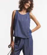 Musculosa de jeans color azul con recortes y cierre por botón.