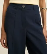 Pantalón de vestir azul marino, de corte recto, con bolsillos laterales y traseros. Se ajusta a la cintura con cinturón de cuero marrón.