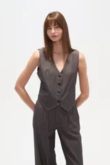 Chaleco de vestir sin mangas, color negro con finas rayas verticales blancas. Presenta escote en V, cierre frontal con botones y bolsillos falsos a la altura de la cintura.