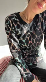 Sweater de punto con cuello en V y estampado abstracto en tonos negro, azul, rosa y verde.