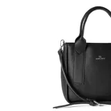 Cartera negra de símil cuero graneado, con acceso por cierre y herrajes plateados. Tiene correa regulable y asas fijas, un bolsillo interno con cierre y un compartimento principal.