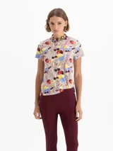Remera de algodón pima con estampado de cerezas y otros motivos abstractos en colores rojo, amarillo, azul y gris. Presenta escote redondo, mangas cortas y una pequeña boca bordada en el delantero.
