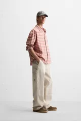 Pantalón color marrón con efecto lavado, corte relaxed fit, cinco bolsillos, aplicación de tira y bolsillo multifunción en perneras, cierre frontal con cremallera y botón.
