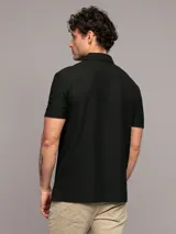 Chomba negra de manga corta con cuello polo y cremallera corta en el frente. Logo de Calvin Klein bordado en el pecho.