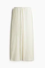Pantalón de corte ancho color crema, con textura arrugada y cintura elástica con cordón ajustable.