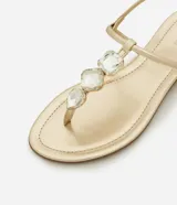 Sandalia plana dorada con tiras finas y aplicación de pedrería.