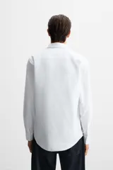 Camisa blanca de algodón, corte slim fit, cuello italiano, manga larga con puños abotonados y cierre frontal con botones.