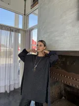 Sweater de punto color gris oscuro con detalles brillantes, de corte amplio y mangas largas con puños ajustados.