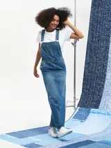 Jumper largo de denim azul con breteles regulables, bolsillos frontales y corte recto.