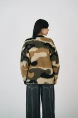 Sweater oversized con estampado camuflado en tonos marrón, verde y negro, de textura suave cepillada. Tiene cuello redondo y corte relajado.