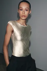 Camiseta dorada de cuello redondo y manga corta, con tejido metalizado.