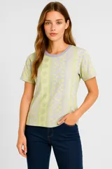 Remera amarilla con estampado de motivos playeros en blanco: soles, olas y conchas marinas.