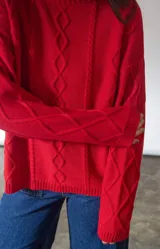 Sweater rojo de punto con diseño de rombos en relieve, corte holgado y cuello redondo.