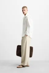 Camisa de algodón color blanco hueso, de corte relajado (relaxed fit), con cuello solapa y manga larga terminada en puño con botón. Cierre frontal con botonadura.