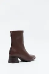 Bota corta de caña elástica color negro, con puntera cuadrada y taco geométrico de altura media. Presenta cierre de cremallera en la parte trasera.