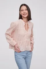 Blusa blanca con rayas verticales, cuello con lazo, mangas largas y corte holgado.