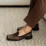 Mocasines negros de cuero con textura tipo reptil, punta cuadrada y detalle de aplique de cuero liso en el empeine.