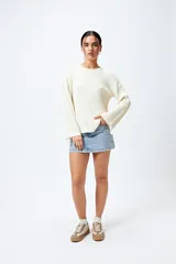 Sweater negro de punto canalé con detalle de trenzado en las mangas y lazo ajustable en el ruedo.