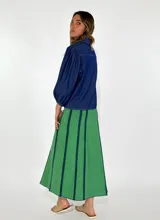 Pollera larga de jean azul con corte acampanado y costuras verticales en color ladrillo.