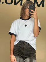 Remera blanca de algodón con cuello redondo y mangas cortas con puños de lurex negro.