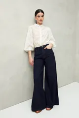 Pantalón de jean negro de calce ultra wide leg, tiro alto y silueta amplia desde la cadera hasta el bajo. Diseño clásico de cinco bolsillos y cierre con botón metálico y cremallera.