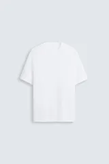 Camiseta blanca de punto tejido en hilatura de algodón, corte regular fit, cuello redondo y manga corta con terminaciones en rib.