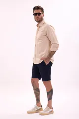 Camisa de manga larga color beige claro, de corte clásico y confeccionada en tejido texturizado.