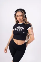 Remera corta de jersey color rosa con cuello redondo y mangas cortas con ribete blanco. Estampado frontal con la inscripción "ST-TROPEZ" en letras blancas.