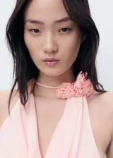 Blusa sin mangas color rosa, con cuello drapeado y detalle de flores en el cuello.