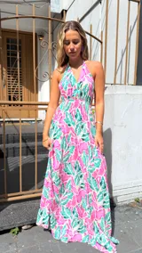 Vestido largo con estampado de hojas en tonos rosa y verde, escote halter y cintura elastizada.