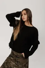 Buzo negro de punto con lanilla tipo canelon, corte flojo, mangas caídas y aberturas laterales.